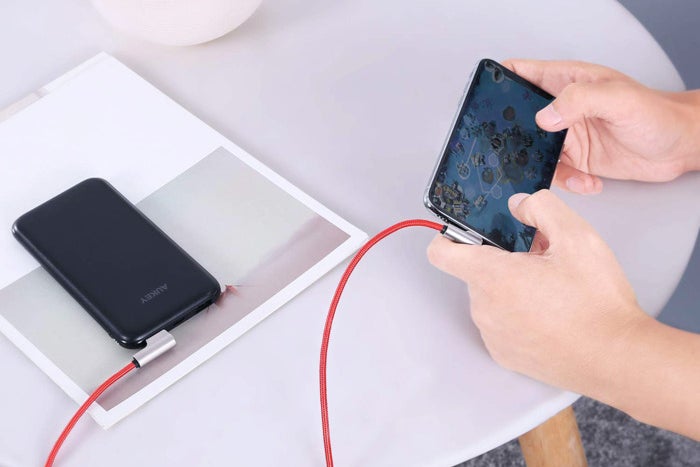 Two smartphones connected to Aukey lightning cables.